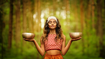 Indian Woman with Tibetan Singing Bowls Outdoors. Yoga Meditation Practice in Forest. Spiritual Sound Healing Therapy. Peaceful Nature Relaxation