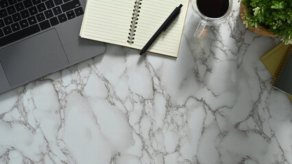 Feminine workspace with laptop, notepad and coffee cup on marble table. Top view with copy space