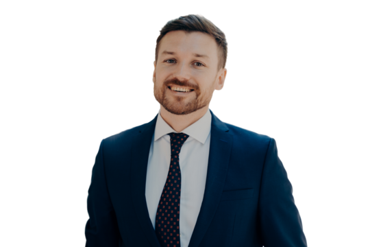 Close portrait of smiling handsome young bearded man in dark blue suit walking outside in sunny day along green alley in city centre, happy to receive promotion at work today