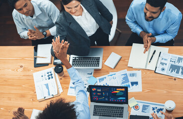Top view diverse business team celebrate successful meeting with high-fives and expressions of...