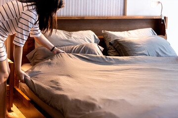 Asian woman making bed arranging blanket,changing bedding in her room,Housewife cleaning,tidying up...