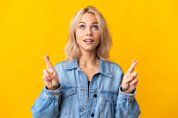 Young Russian woman isolated on yellow background with fingers crossing and wishing the best