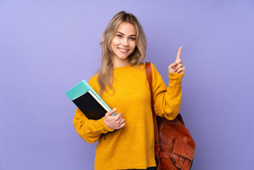 Teenager Russian student girl isolated on purple background showing and lifting a finger in sign of...