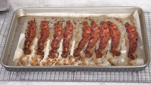 Step by step. Cooked bacon strips on a baking sheet with white parchment paper.