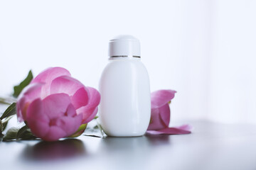 Bottle of white cream and pink flowers