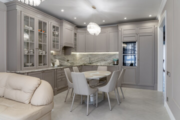 Modern beige and grey colored kitchen interior in classic style with dining table in luxury home