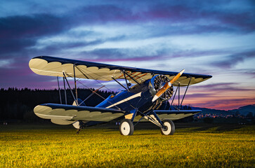 Parked vintage bi-plane photographed during sunset. This plane has a radial engine and an open...