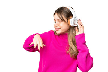 Young girl over isolated chroma key background listening music and dancing