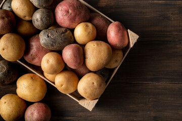 Fresh multi-colored potatoes on a wooden background.