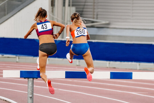 back two woman athlete running steeplechase is obstacle race in summer athletics championships