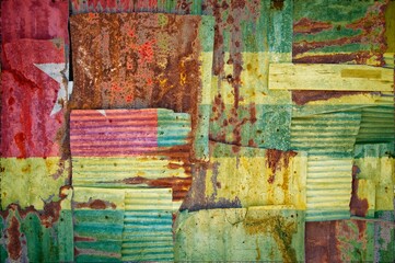 Flag of Togo painted onto rusty corrugated iron sheets overlapping to form a wall or fence