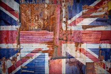 Flag of United Kingdom painted onto rusty corrugated iron sheets overlapping to form a wall or fence