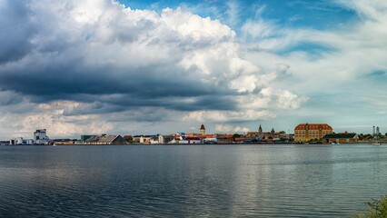 Fototapeta na wymiar Seaside view to the old town under big white clouds, Nykobing Falster, Denmark