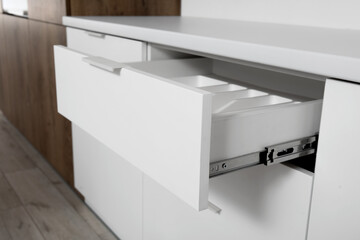Open white drawer in light kitchen