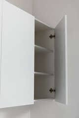 White cupboard hanging on light wall in kitchen