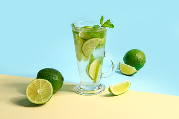 Glass of cold mojito and lime on colorful background