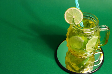 Mason jar of cold mojito on green background
