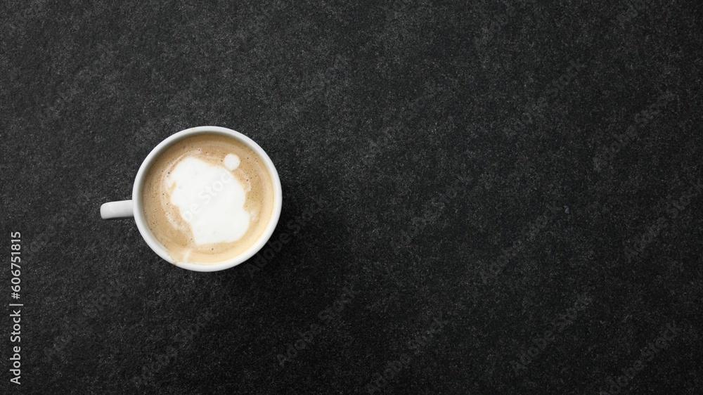 Sticker top-view of a fresh cappuccino in a white mug on a textured black background