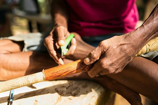 Hands of a person carving on the surface of the blowpipe