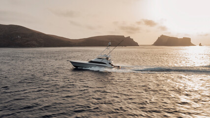 Sport fishing boat in profile against a backdrop of rugged mountainous shores