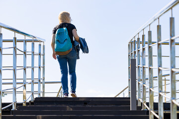 a girl with a backpack climbs the stairs