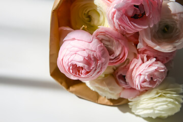 Bouquet of Ranunculus beautiful delicate flowers. Floral decor. Bright sunlight and shadows on a white surface.