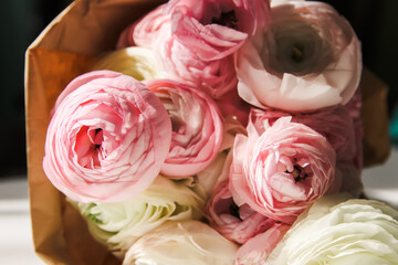 Bouquet of Ranunculus beautiful delicate flowers. Floral decor. Bright sunlight and shadows on a white surface.