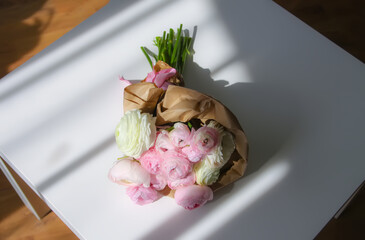 Bouquet of Ranunculus beautiful delicate flowers. Floral decor. Bright sunlight and shadows on a white surface.