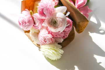 Bouquet of Ranunculus beautiful delicate flowers. Floral decor. Bright sunlight and shadows on a white surface.