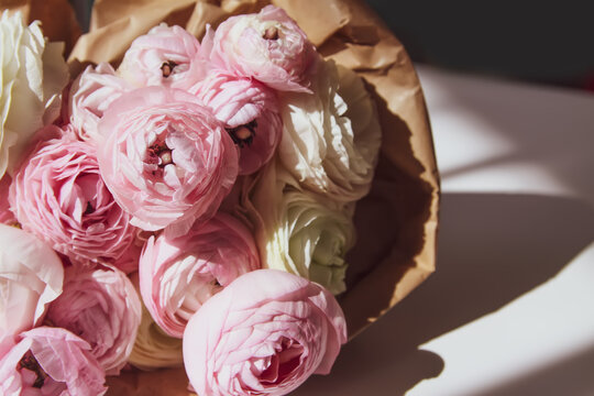 Bouquet of Ranunculus beautiful delicate flowers. Floral decor. Bright sunlight and shadows on a white surface.