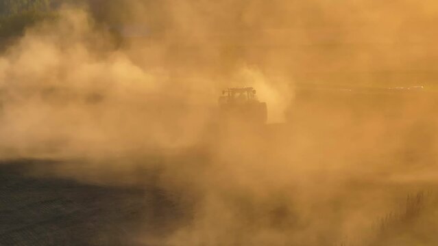Farmer in a tractor in a dust cloud, agriculture in spring