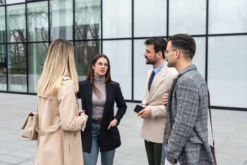 Group of business people discussing ideas at meeting outside. Businesswoman and businessman outdoor near office building talking about opportunities and solutions for new company.