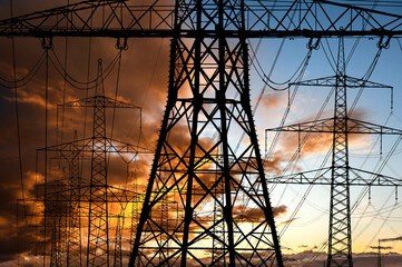 high voltage electric pylons against sky with dramatic clouds