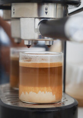 A clear glass cup of dirty coffee latte on espresso machine make. It's a coffee consists of cold milk, sometimes a mixture of milk and cream, combined with solid espresso or ristretto