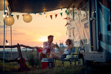 A young couple is sitting in the camp during vacation and drinking. Vacation, relationship, camping, nature