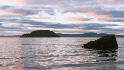 Beautiful view of rock on a lake under the cloudy sky during sunrise