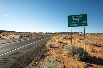 Green city limits sign entering Page, Arizona on the side of a road