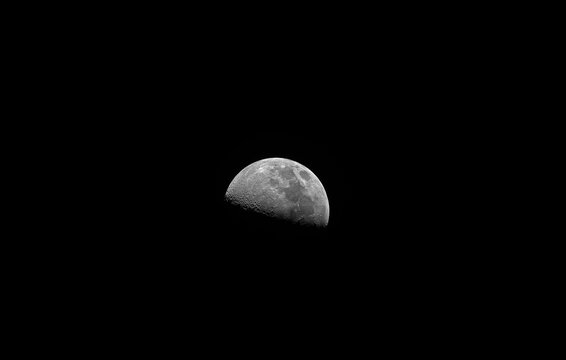 First quarter Moon phase, a large field of view, taken with refractor telescope, isolated in a black bacgound without stars.