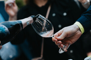 Rose wine poured into a glass by a waiter at a tasting in a restaurant.