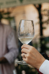 White wine poured into a glass by a waiter at a tasting in a restaurant. - 606766435