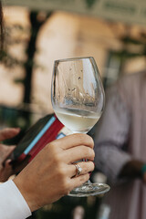 White wine poured into a glass by a waiter at a tasting in a restaurant. - 606766443