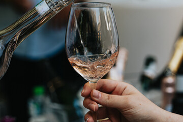 Rose wine poured into a glass by a waiter at a tasting in a restaurant. - 606766463
