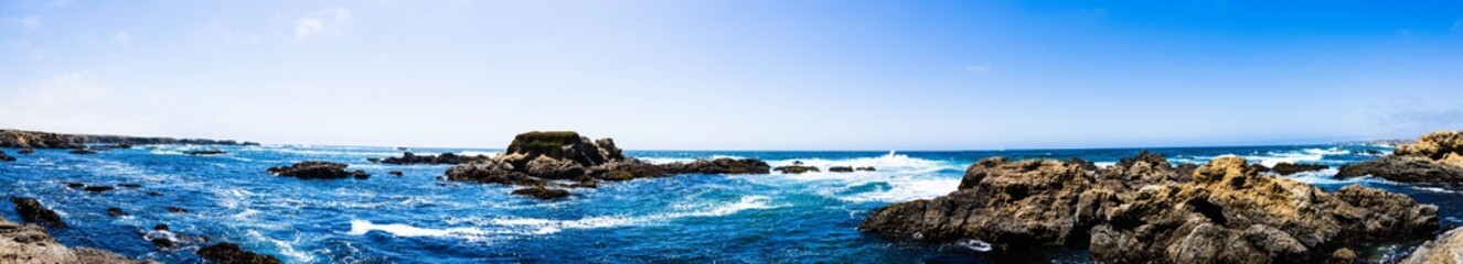 Panoramic shot of beautiful rocky coastline and undulating ocean in harmony with blue sky © Brian Jones/Wirestock Creators