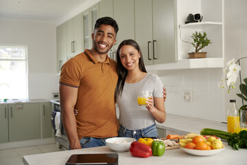 Obraz na płótnie Canvas Young biracial couple in casual clothing smiling and looking at camera by food in kitchen