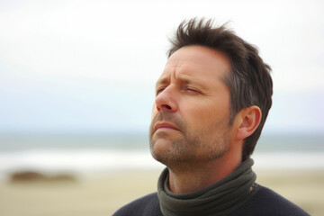 Portrait of a man with eyes closed on a beach in autumn