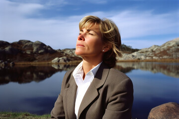 Fototapeta premium Beautiful businesswoman sitting on the bank of a mountain lake.