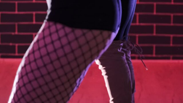 Group of elegant women in fishnet stockings and high heels performing on pink lit stage of night club. Erotic show for adults