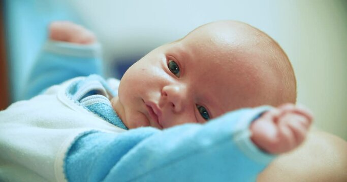 A yawning three-month-old boy lies and looks into the camera. White American baby.