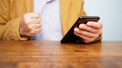 Cheerful man congratulating success clenched his fists. smartphone in hand