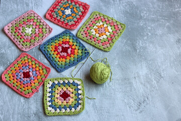 Colorful crochet Granny squares on light grey background with copy space. Handmade blanket in...